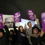 Activists chant slogans in Tel Aviv, Israel, to protest against Prime Minister Benjamin Netanyahu's far-right government, Saturday, Jan. 7, 2023. The placard at left reads: "The settler government is against me."; the placard at right reads: "housing, livelihood, hope." (AP Photo/ Tsafrir Abayov)