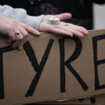 
              A demonstrators holds a sign and candle as they protest outside a police precinct in response to the death of Tyre Nichols, who died after being beaten by Memphis police officers, in Memphis, Tenn., Sunday, Jan. 29, 2023. (AP Photo/Gerald Herbert)
            