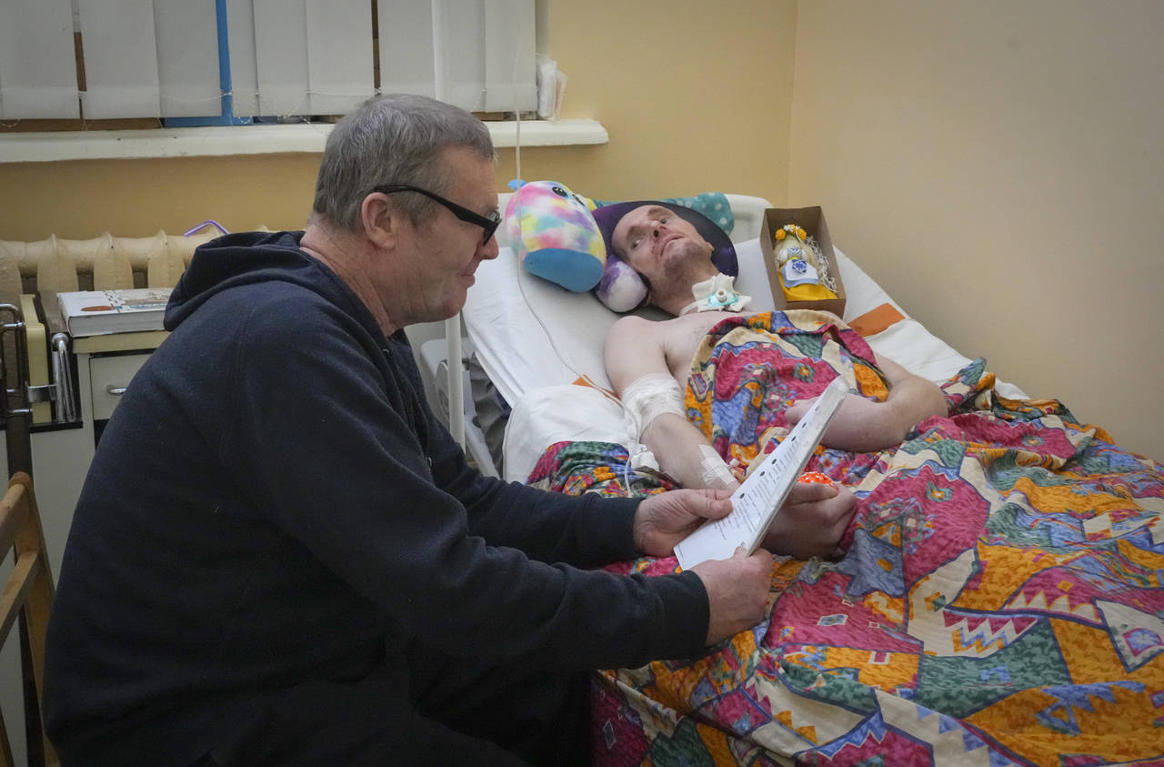 Serhii Shumei, 64, reads letters with recovery wishes to his son Vitalii, 34, a Ukrainian officer h...