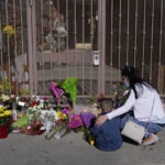 
              A woman comforts her son while visiting a makeshift memorial outside Star Dance Studio in Monterey Park, Calif., Monday, Jan. 23, 2023. Authorities searched for a motive for the gunman who killed 10 people at the ballroom dance club during Lunar New Year celebrations. (AP Photo/Jae C. Hong)
            