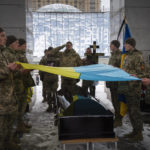 Ukrainian soldiers hold their national flag over the coffin of comrade Denis Galushko, during a commemoration ceremony in Independence Square in Kyiv, Ukraine, Sunday, Jan. 12, 2023. The 38-year-old soldier died during a combat mission in the Donetsk region. (AP Photo/Efrem Lukatsky)