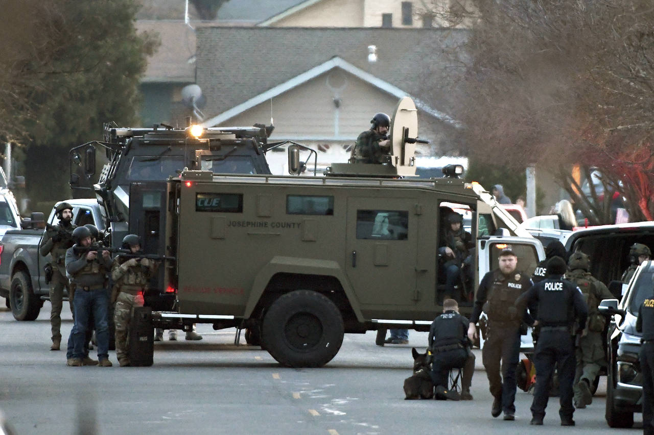 Law enforcement officers aim their weapons at a home during a standoff in Grants Pass, Ore., on Tue...