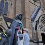 
              A protester ties ribbons as a symbol of support to sex abuse victims to a statue of Saint Mary MacKillop at St. Mary's Cathedral where Cardinal George Pell's coffin will be brought to lay in state in Sydney, Wednesday, Feb. 1, 2023. Pell, who was once considered the third-highest ranking cleric in the Vatican and spent more than a year in prison before his child abuse convictions were squashed in 2020, died in Rome last month at age 81. (AP Photo/Rick Rycroft)
            