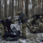 
              Military medics give first aid to a wounded soldier, right, and place the a body of a killed soldier into a bag, near Kremenna in the Luhansk region, Ukraine, Monday, Jan. 16, 2023. (AP Photo/LIBKOS)
            