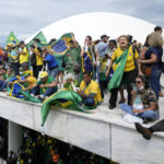 
              Protesters, supporters of Brazil's former President Jair Bolsonaro, stand on the roof of the National Congress building after they stormed it, in Brasilia, Brazil, Sunday, Jan. 8, 2023. (AP Photo/Eraldo Peres)
            
