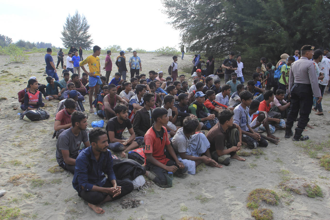 Ethnic Rohingya people sit on a beach after they landed in Aceh Besar, Indonesia, Sunday, Jan. 8, 2...