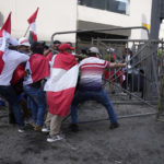 
              Anti-government protesters who traveled to the capital from across the country to march against Peruvian President Dina Boluarte, tear down a police barricade during clashes in Lima, Peru, Thursday, Jan. 19, 2023. Protesters are seeking immediate elections, Boluarte's resignation, the release of ousted President Pedro Castillo and justice for up to 48 protesters killed in clashes with police. (AP Photo/Martin Mejia)
            
