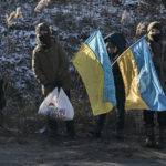 
              Ukrainian children hold national flags as they stand guard at an improvised checkpoint close to Sloviansk, Donetsk region, Ukraine, Wednesday, Jan. 11, 2023.(AP Photo/Libkos)
            