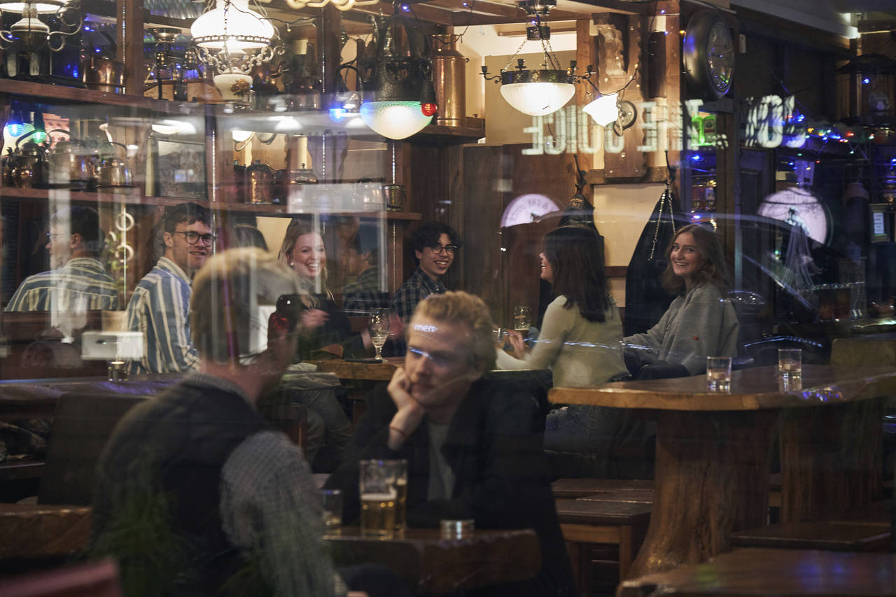 FILE - People sit in a bar in Stockholm, Sweden, on March 25, 2020. Sweden wants to cut red tape wh...