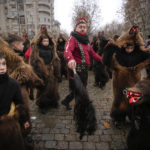 
              People wearing bear fur costumes dance during a parade showcasing winter traditions from the northeast of the country in Bucharest, Romania, Sunday, Dec. 18, 2022. The custom originated in pre-Christian times, when dancers wearing colored costumes or animal furs went village households, singing and dancing to ward off evil. (AP Photo/Andreea Alexandru)
            