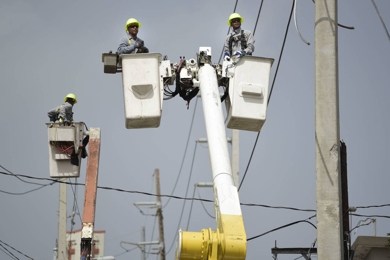 FILE - Puerto Rico Electric Power Authority workers repair distribution lines damaged by Hurricane ...