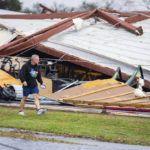 
              A man walks by a former CrossFit gym that collapsed where a tornado was reported to pass along Mickey Gilley Boulevard near Fairmont Parkway, Tuesday, Jan. 24, 2023, in Pasadena, Texas. (Mark Mulligan/Houston Chronicle via AP)
            