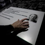 
              Jorge Tredler, 83, of Poland, who came to Brazil with his family in Feb. 1951 after taking refuge in Russia and other countries during the second World War, points to a photo of his mother Irena on an interactive table that tells the stories of thousands of people who took refuge in Brazil during the Holocaust, at the Holocaust Victims Memorial on its opening day to the public in Rio de Janeiro, Brazil, Thursday, Jan. 19, 2023. (AP Photo/Bruna Prado)
            