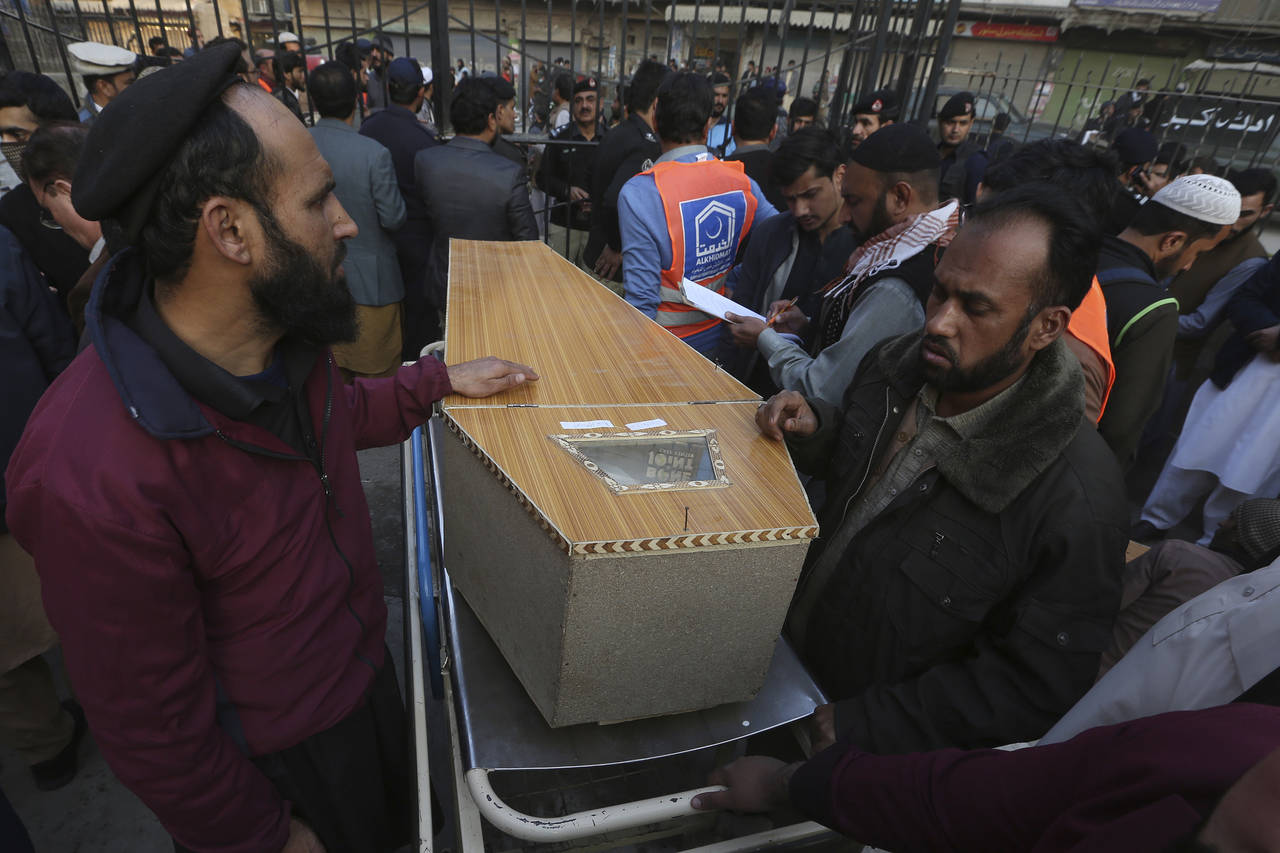 People wait for transport next to a coffin of their relative, killed in the suicide bombing inside ...