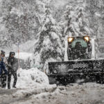 
              Pedestrians walk along a road as a snow plow works in South Lake Tahoe, Calif., Saturday, Dec. 31, 2022. A winter storm warning has been issued for the greater Lake Tahoe area until Sunday. (Stephen Lam/San Francisco Chronicle via AP)
            