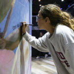 
              Sarah Painter signs a mural at the front set up at the entrance of The Moon a few hours before Vice President Kamala Harris speaks in Tallahassee, Florida in honor of the 50th anniversary of Roe v. Wade on Sunday Jan. 22, 2023. (Alicia Devine/Tallahassee Democrat via AP)
            