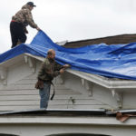 
              Unidentified workers secure a blue tarp on a house in Selma, Ala., Friday, Jan. 13, 2023, after a tornado passed through the area. Rescuers raced Friday to find survivors in the aftermath of a tornado-spawning storm system that barreled across parts of Georgia and Alabama. (AP Photo/Stew Milne)
            