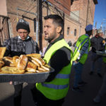 
              Church volunteers serve garlic bread to migrants camping outside the Sacred Heart Church in downtown El Paso, Texas, Sunday, Jan. 8, 2023. President Joe Biden arrived in Texas on Sunday for his first trip to the U.S.-Mexico border since taking office, stopping in El Paso after two years of hounding by Republicans who have hammered him as soft on border security while the number of migrants crossing spirals. (AP Photo/Andres Leighton)
            