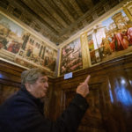 
              Piergiorgo Millich, Grand Guardian, Dalmatian School, Wednesday, Dec. 7, 2022, looks at paintings by Renaissance artist Vittore Carpaccio adorning the ground floor of the Dalmatian School in Venice, Italy, Wednesday, Dec. 7, 2022. From left, St. Tryphon and the Basilisk, a replica of the Agony in the garden which is under restoration by Valentina Piovan at the School, and The risen Christ. On November 20th, the National Gallery of Washington inaugurated the first retrospective exhibition of Carpaccio’s works outside of Italy. It will run until February 12, 2023. (AP Photo Domenico Stinellis)
            