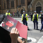 
              A woman uses a program to block the sun as she uses her phone to live stream the funeral of Cardinal George Pell as police guard St. Mary's Cathedral in Sydney, Thursday, Feb. 2, 2023. Pell, who died last month at age 81, spent more than a year in prison before his sex abuse convictions were overturned in 2020. (AP Photo/Rick Rycroft)
            