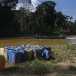 
              Containers used for mining sit on the bank of the Uraricoera River as miners pass by in a boat in Alto Alegre, Roraima state, Brazil, to leave Yanomami Indigenous territory ahead of expected operations against illegal mining, Tuesday, Feb. 7, 2023. The government declared a public health emergency for the Yanomami people in the Amazon, who are suffering from malnutrition and diseases such as malaria as a consequence of illegal mining. (AP Photo/Edmar Barros)
            