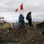 
              FILE - An Aymara woman, holding a Peruvian national, stands on a pile of dirt serving as a roadblock set up by anti-government protesters, in Acora, southern Peru, Jan. 29, 2023. Peruvians have been protesting since early December, when former President Pedro Castillo was impeached after a failed attempt to dissolve Congress. His vice president, Boluarte, immediately took over — and has faced strong opposition ever since. (AP Photo/Rodrigo Abd, File)
            
