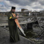 
              A Ukrainian military priest stands on the edge of a destroyed bridge in Irpin, on the outskirts of Kyiv, Ukraine, Wednesday, March 9, 2022. (AP Photo/Vadim Ghirda)
            