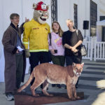 
              People pose for pictures next to a cardboard cutout of Hollywood's most famous mountain lion, P-22, during his public memorial put on by the "Save LA Cougars," at the Greek Theater in Griffith Park in Los Angeles Saturday, Feb. 4, 2023. (AP Photo/Stefanie Dazio)
            
