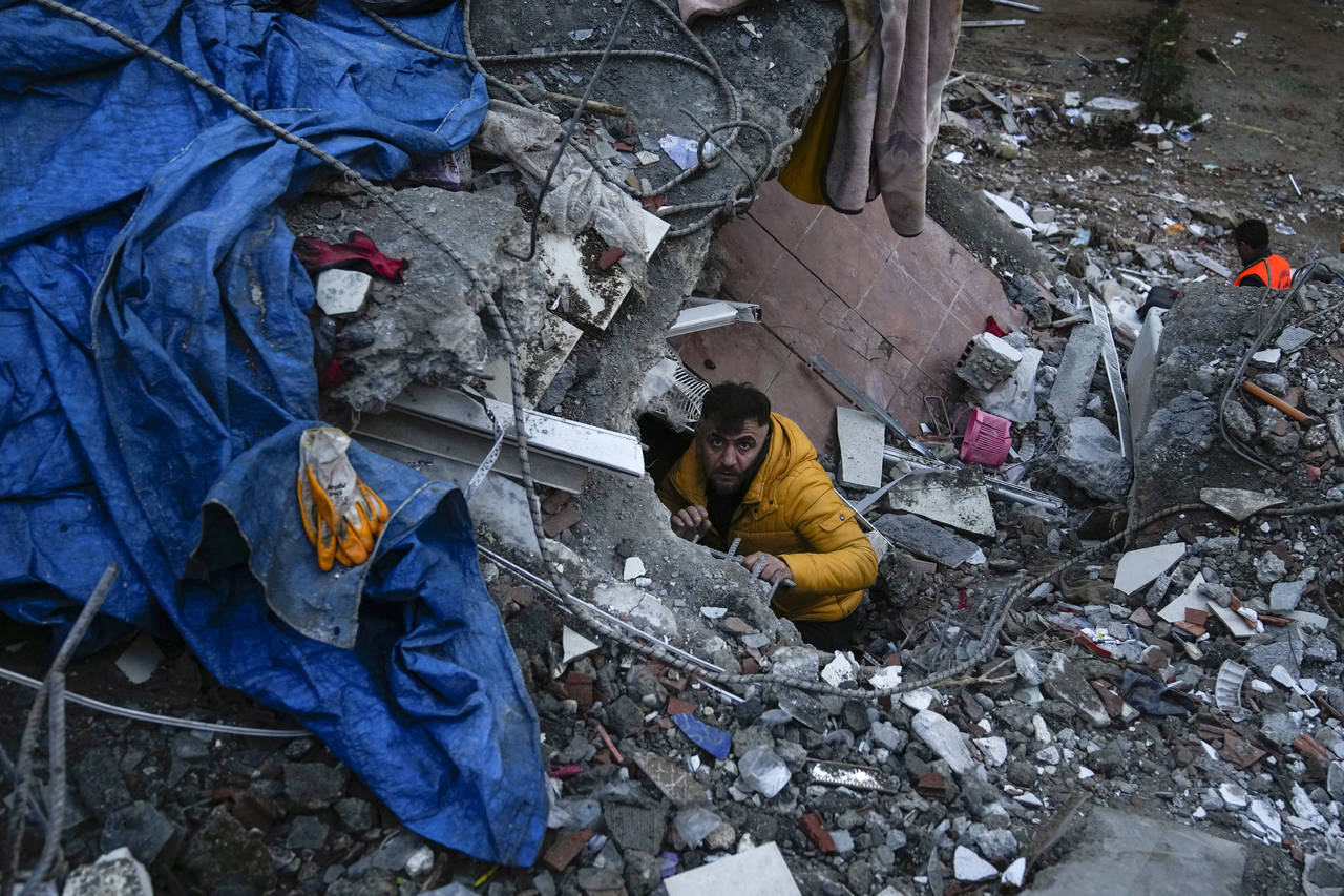 A man searches for people in a destroyed building in Adana, Turkey, Monday, Feb. 6, 2023. A powerfu...