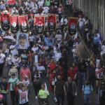 
              Demonstrators carry Sandinista National Liberation Front banners and a portrait of President Daniel Ortega and Vice President Rosario Murillo, during a pro-government march in Managua, Nicaragua, Saturday, Feb. 11, 2023.  (AP Photo)
            