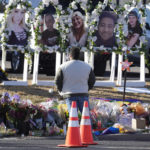
              FILE - A person pauses to pay respects as portraits of the victims of a mass shooting at a gay nightclub are displayed at a makeshift memorial Nov. 22, 2022, near the scene in Colorado Springs, Colo. A court hearing is scheduled to start Wednesday, Feb. 22 ,for the 22-year-old suspect in the shooting. (AP Photo/David Zalubowski, File)
            