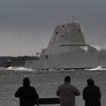 
              FILE — Spectators watch the USS Lyndon B. Johnson Zumwalt-class destroyer travel down the Kennebec River on its way to sea Jan. 12, 2022, in Phippsburg, Maine. The U.S. Navy, following costly lessons after cramming too much new technology onto warships and speeding them into production, is slowing down the design and purchase of its next-generation destroyer, and taking extra steps to ensure new technology like lasers and hypersonic missiles have matured before pressing ahead. (AP Photo/Robert F. Bukaty, File)
            