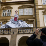 
              A man takes a photo of an art piece, done by street artist "Chemis", to mark the first anniversary of Russia's full-scale invasion of Ukraine, downtown Prague, Czech Republic, Friday, Feb. 24, 2023. (AP Photo/Petr David Josek)
            