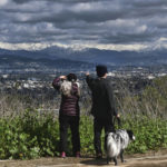 
              People take photos and view snow covering the San Gabriel mountain range from Kenneth Hahn State Recreational Area in Los Angeles on Sunday, Feb. 26, 2023. (AP Photo/Richard Vogel)
            