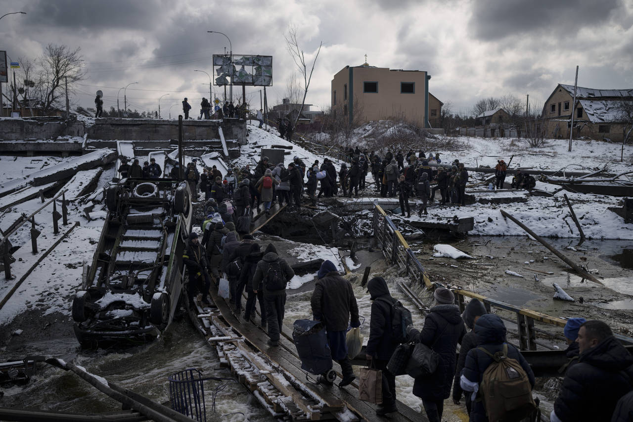 FILE - Ukrainians cross an improvised path under a destroyed bridge while fleeing Irpin, in the out...