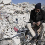 
              A man sits in the rubble of a destroyed building in Atareb, Syria, Sunday, Feb. 12, 2023. Six days after a massive earthquake killed thousands in Syria and Turkey, sorrow and disbelief are turning to anger and tension over a sense that there has been an ineffective, unfair and disproportionate response to the historic disaster. (AP Photo/Hussein Malla)
            