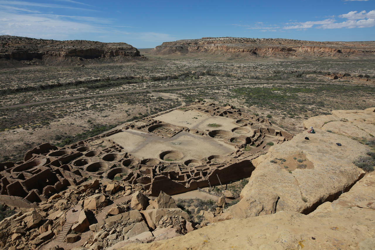 FILE - A hiker sits on a ledge above Pueblo Bonito, the largest archeological site at the Chaco Cul...