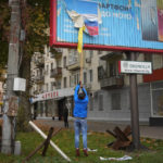 
              FALTA 13, 28 FILE - A local resident removes the Russian flag from a billboard in central Kherson, Ukraine, Nov. 13, 2022. Ukraine liberated Kherson more than one week ago, and the city's streets are revived for the first time in many months. People no longer sit in their homes in fear of meeting the Russians. Instead, they gather in the city's squares to recharge their phones, collect water and catch a connection to talk to their relatives. (AP Photo/Efrem Lukatsky, file)
            