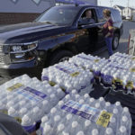 
              Becky Rance, center, talks with a Police officer as she hands out water from the back of her truck in downtown East Palestine, Ohio, as the cleanup of portions of a Norfolk Southern freight train that derailed over a week ago continues, Wednesday, Feb. 15, 2023. (AP Photo/Gene J. Puskar)
            