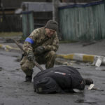 
              FILE - A Ukrainian serviceman uses a piece of wood to check if the body of a man dressed in civilian clothing is booby-trapped with explosive devices, in the formerly Russian-occupied Kyiv suburb of Bucha, Ukraine, Saturday, April 2, 2022. (AP Photo/Vadim Ghirda, File)
            