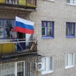 
              FILE - In this handout photo taken from video released by the Russian Defense Ministry Press Service on Monday, July 4, 2022, A man sets a Russian national flag on a balcony of a residential building in Lysychansk, which is now territory under the Government of the Luhansk People's Republic control, eastern Ukraine. (Russian Defense Ministry Press Service via AP, File)
            