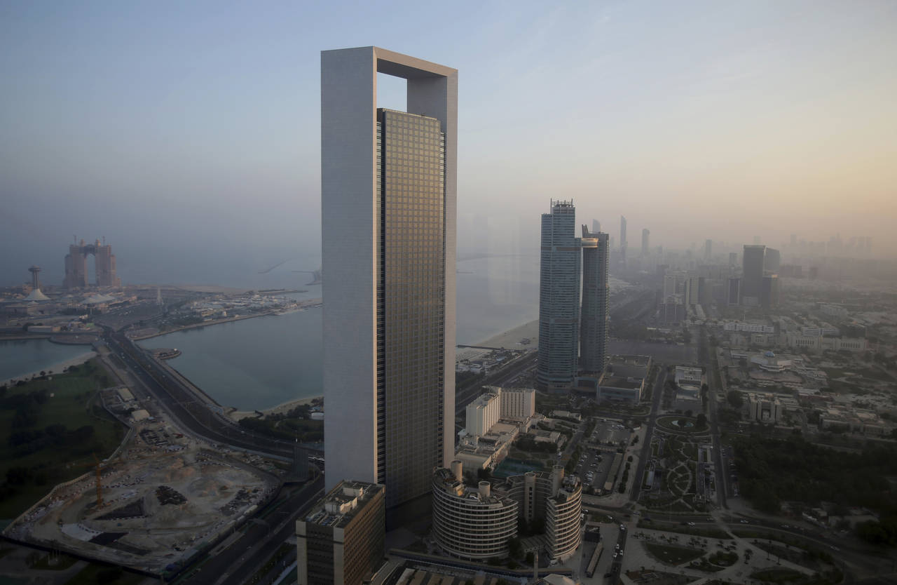 FILE - The sun rises over the headquarters of the Abu Dhabi National Oil Co. headquarters that domi...