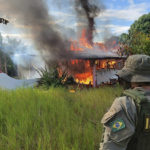 
              In this image provided by IBAMA, Brazil's Environmental Agency, an agent watches as a structure and plane belonging to miners is engulfed in flames in the Yanomami Indigenous territory, Roraima state, Brazil, Feb. 6, 2023. Brazilian authorities launched an operation to reclaim Yanomami Indigenous territory from thousands of illegal gold miners who have contaminated rivers and brought famine and disease to one of the most isolated populations of the world. (IBAMA via AP)
            