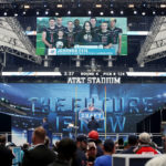 
              FILE - Johanna Feis, sister of football coach Aaron Feis, and members of the Marjory Stoneman Douglas High School football team appear on a screen announcing the Miami Dolphins' fourth-round pick, tight end Durham Smythe from Notre Dame, during the NFL football draft in Arlington, Texas, Saturday, April 28, 2018. (Jae S. Lee/The Dallas Morning News via AP, File)
            