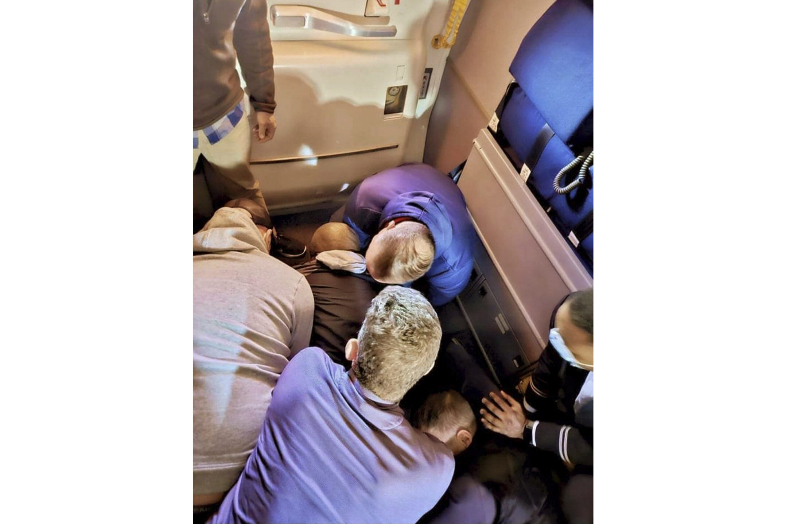 FILE — This image provided by Simik Ghookasian shows passengers and crew members restraining a ma...