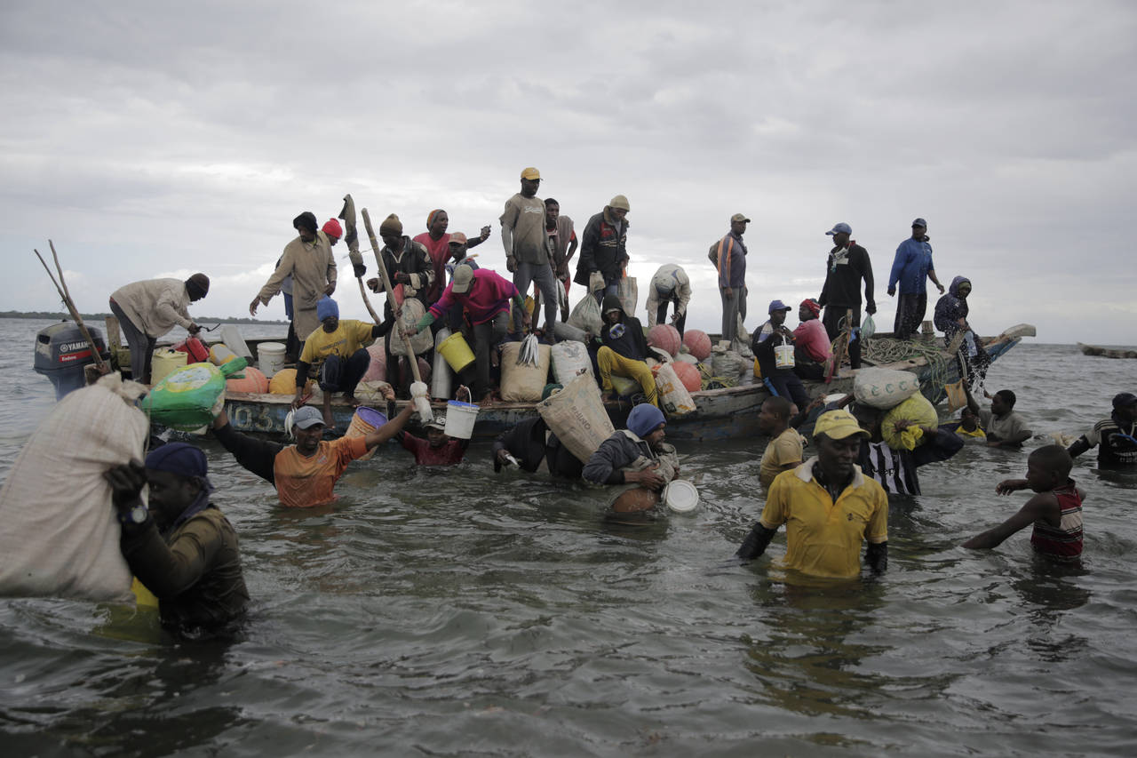 FILE - Fishermen swim out from an incoming boat at a berth, some with their overnight catch in Kwal...