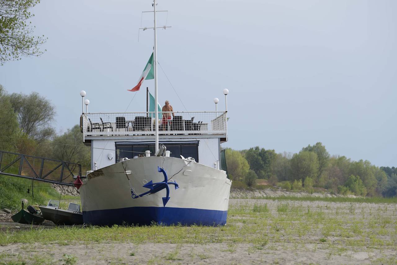 FILE - A boat restaurant lies on the dried riverbed at a tourist dock along the Po river in Ficarol...