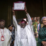 
              President-Elect Bola Tinubu, center, displays his certificate, accompanied by his wife Oluremi Tinubu, right, and chairman of the Independent National Electoral Commission (INEC) Mahmood Yakubu, left, at a ceremony in Abuja, Nigeria Wednesday, March 1, 2023. Election officials declared Tinubu the winner of Nigeria's presidential election Wednesday, keeping the ruling party in power in Africa's most populous nation. (AP Photo/Ben Curtis)
            