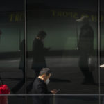 
              People wearing face masks are reflected in windows as they walk at a shopping and office complex in Beijing, Wednesday, March 1, 2023. (AP Photo/Mark Schiefelbein)
            