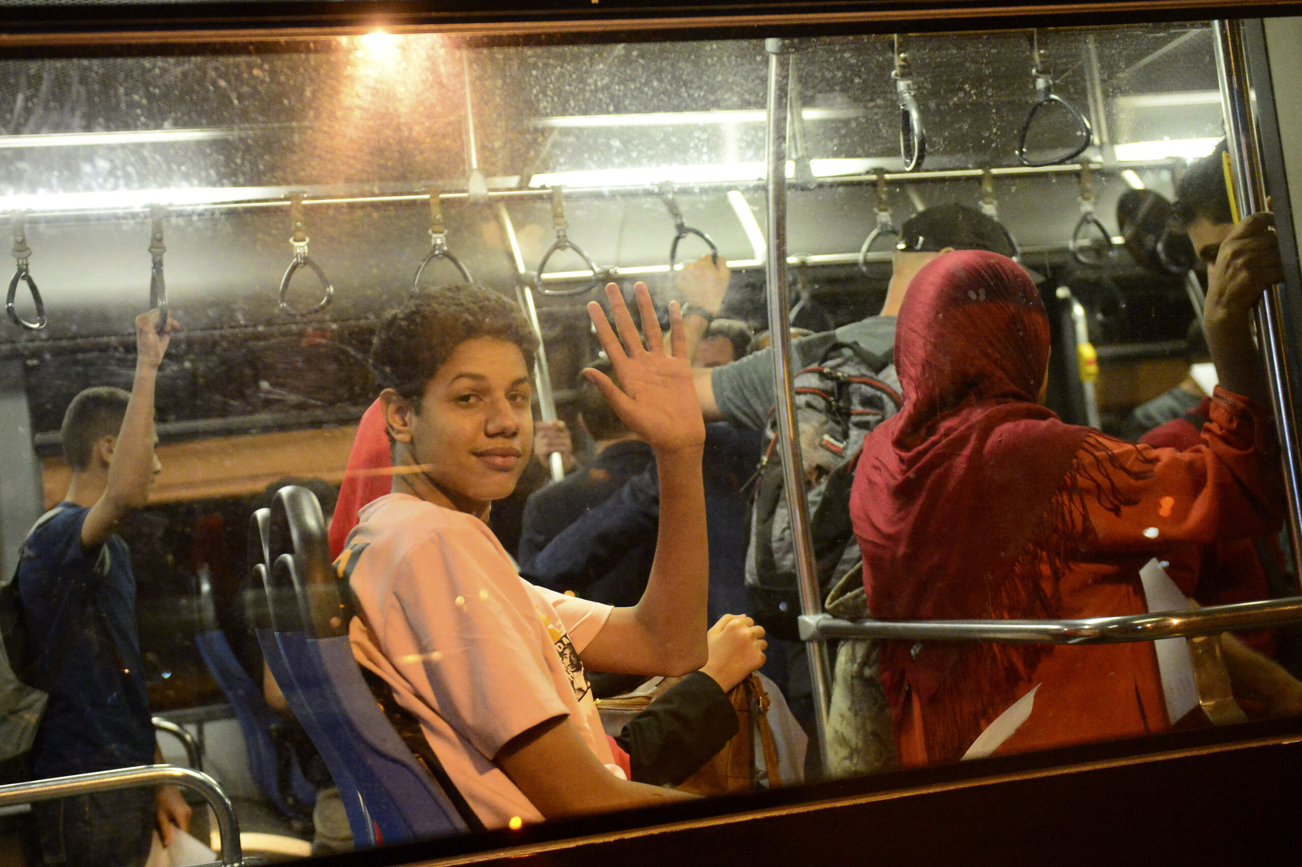 People wave from a bus after arriving in a military plane from Khartoum at the Houari-Boumediene ai...